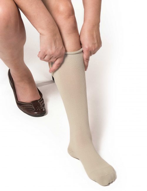 Woman applying tan EXTREMIT-EASE Garment Liner on her left leg