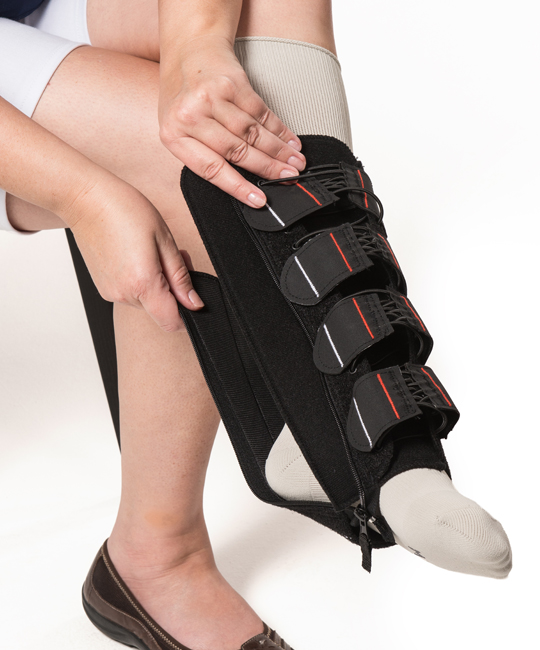 Woman sliding the EXTREMIT-EASE Compression Garment over her foot and on to her leg